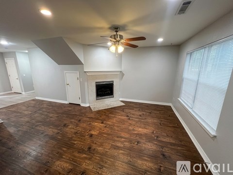 A room with a fireplace and wood flooring.