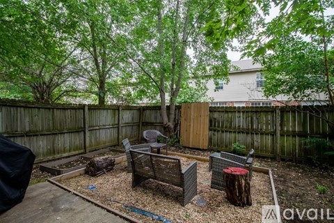 A backyard with a wooden fence and a tree.