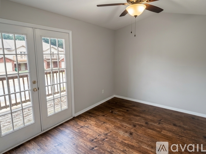 A room with a ceiling fan and a view of a house through the window.