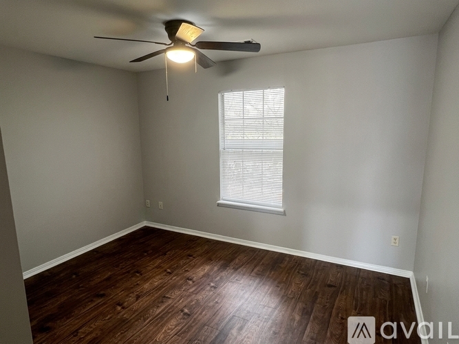 A room with a ceiling fan and wooden flooring.