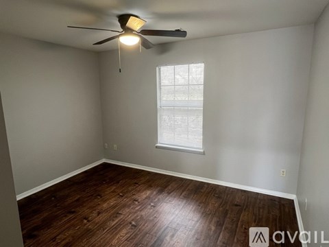 A room with a ceiling fan and wooden flooring.