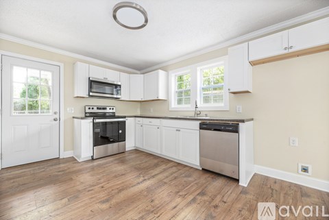 A kitchen with white cabinets and a wooden floor.