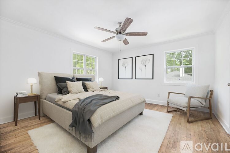 A bedroom with a bed, chair, and pictures on the wall.