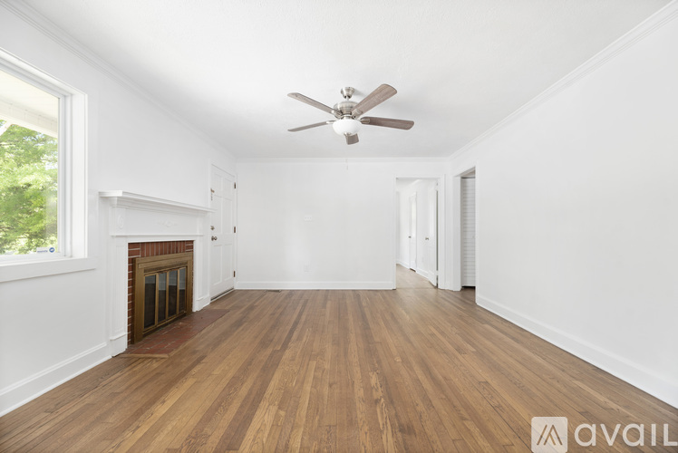 A spacious room with wooden floors and a ceiling fan.