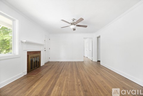 A spacious room with wooden floors and a ceiling fan.