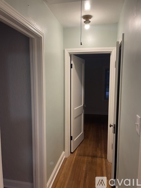 A hallway with a light hanging from the ceiling and a door at the end.