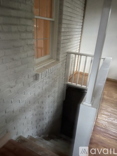 A stairwell with a wooden floor and a white railing.