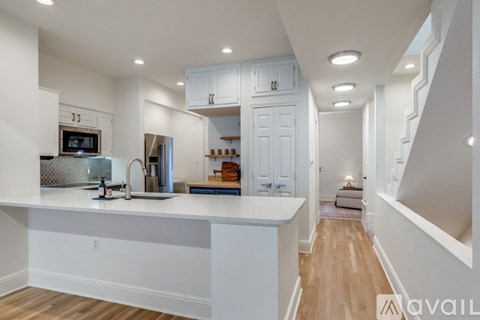A modern kitchen with white cabinets and a wooden floor.