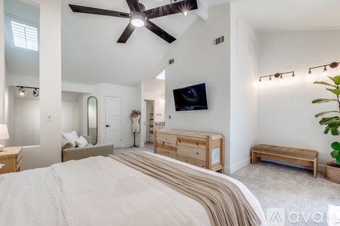 A bedroom with a large bed and a ceiling fan.