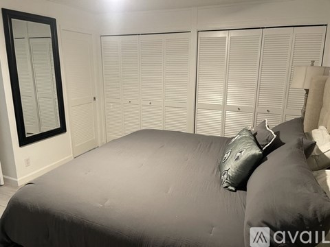 A bedroom with a large bed and a mirror on the wall.
