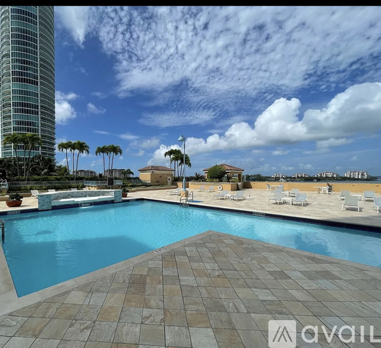 A large swimming pool with a tiled floor and a tall building in the background.