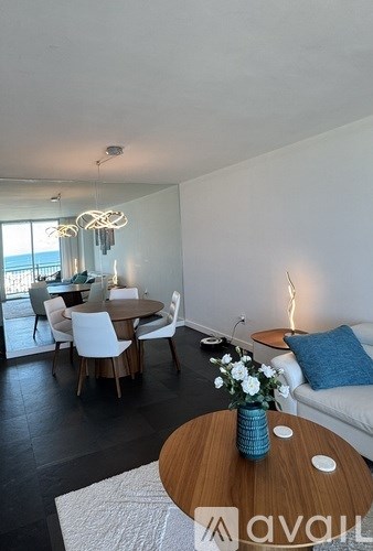 A living room with a white couch, a wooden coffee table, and a dining table with chairs.