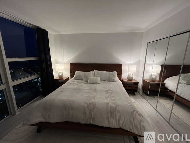 A bedroom with a large bed and a view of the city at night.