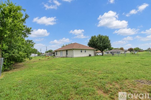 A grassy field with a house and trees in the distance.