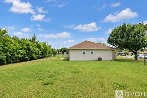 A house with a brown roof is surrounded by a grassy field.