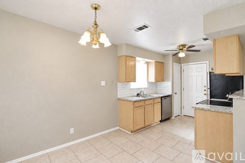 A kitchen with beige cabinets and a black countertop.