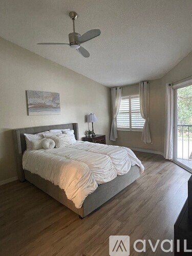 A bedroom with a bed, a ceiling fan, and a painting on the wall.