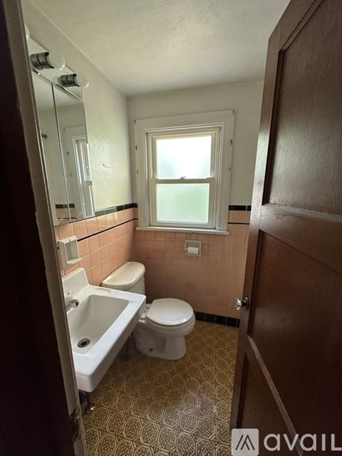 A bathroom with a toilet, sink, and a window.