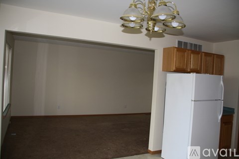 A room with a white fridge and brown carpet.