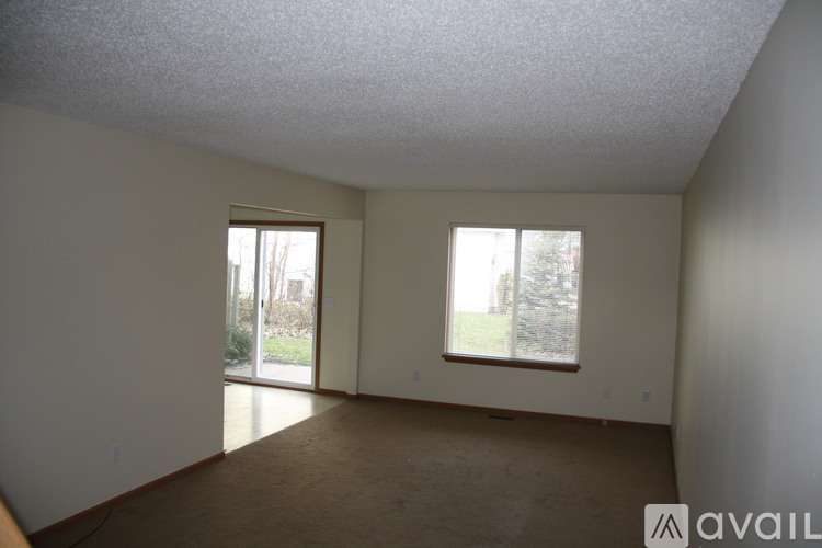 A room with a carpeted floor and two windows.