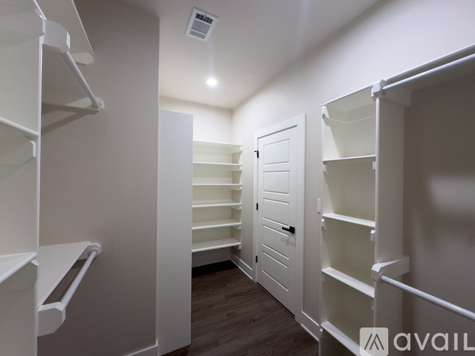 A white walk-in closet with shelves and a door.