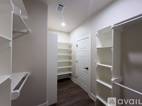 A white walk-in closet with shelves and a door.