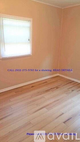 A room with a window and a phone number on the wall.