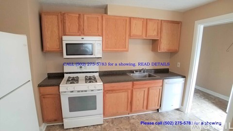 A kitchen with wooden cabinets and a white stove top oven.