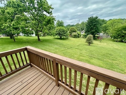 A wooden deck overlooks a lush green lawn and trees.
