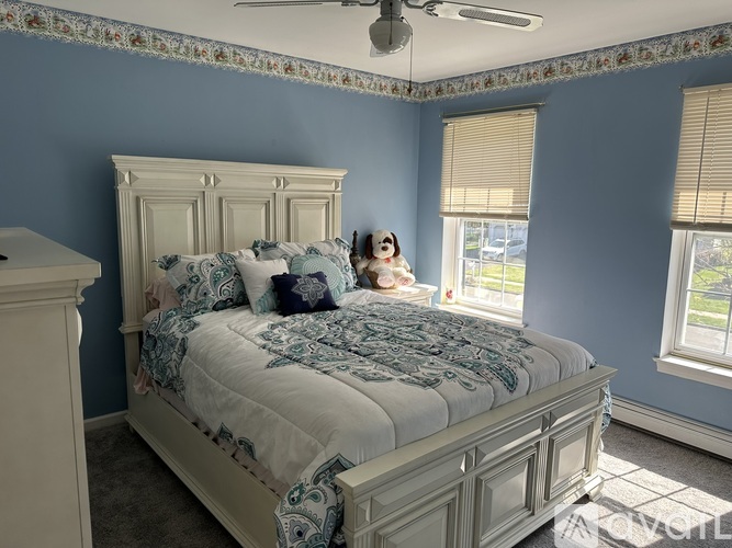 A bedroom with a large bed and a dog on the bed.