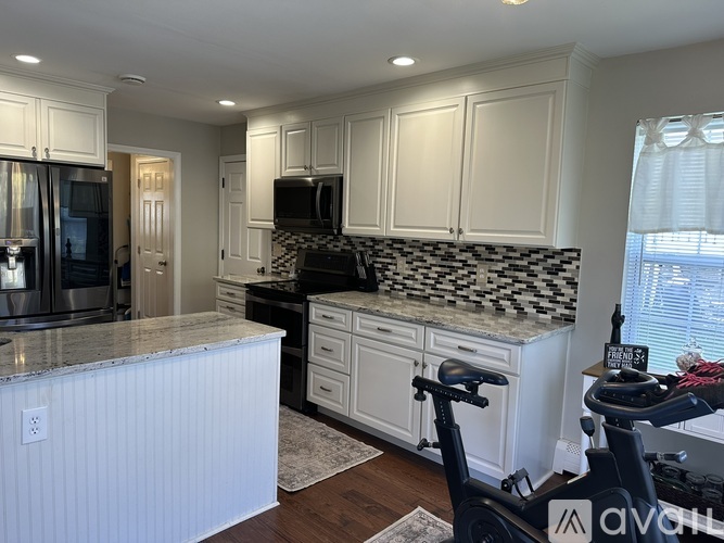 A kitchen with white cabinets and a black and white tiled backsplash.