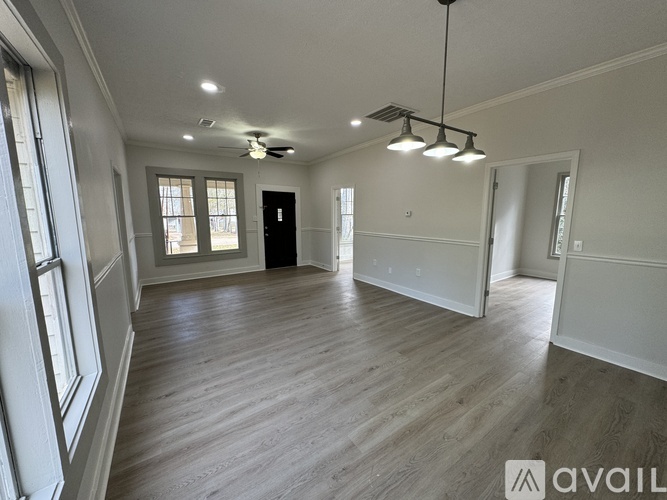A spacious room with wooden flooring and a black door.