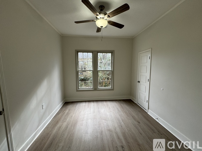 A room with a ceiling fan and a window with a view of trees.