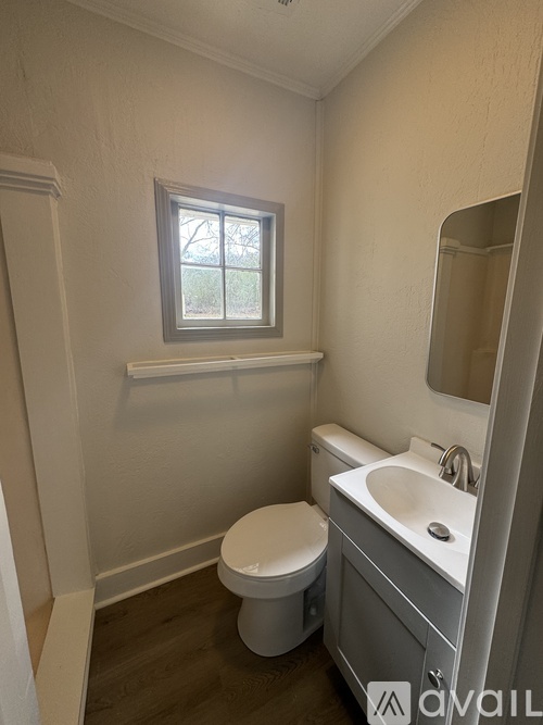 A small bathroom with a toilet, sink, and a window.