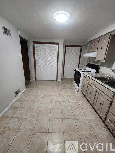 A kitchen with white cabinets and a tiled floor.