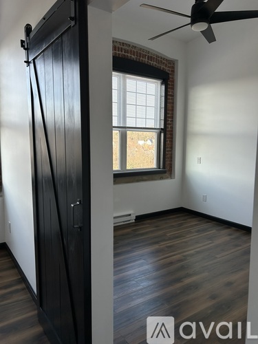 A room with a black door and a ceiling fan.
