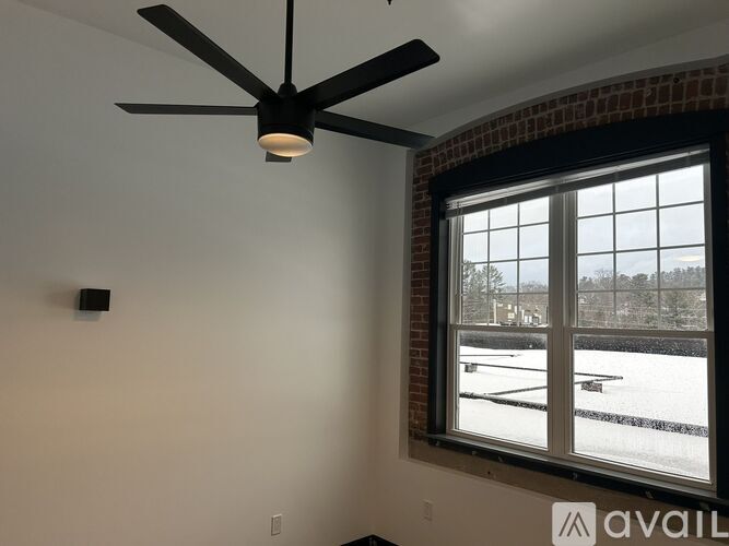 A room with a ceiling fan and a window showing a snowy landscape outside.