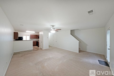 A spacious living room with a carpeted floor and a ceiling fan.