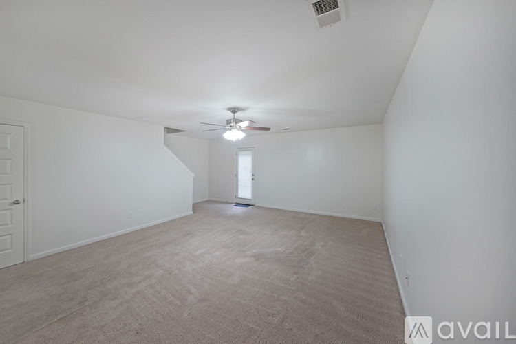 A spacious room with a carpeted floor and a ceiling fan.