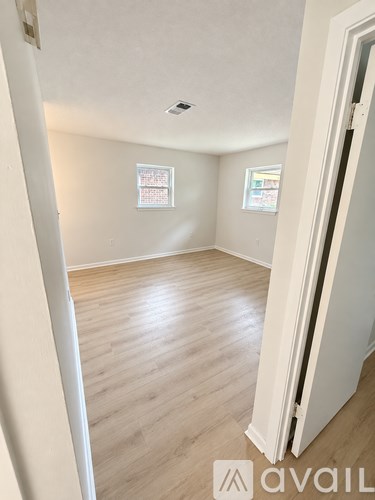 A room with wooden flooring and white walls.