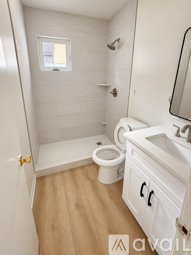 A white bathroom with wooden floors and a toilet.