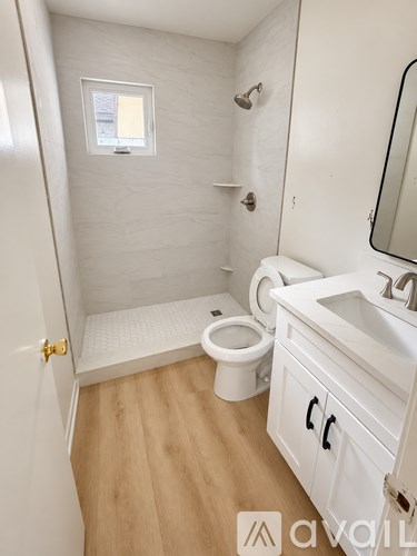 A white bathroom with wooden floors and a toilet.