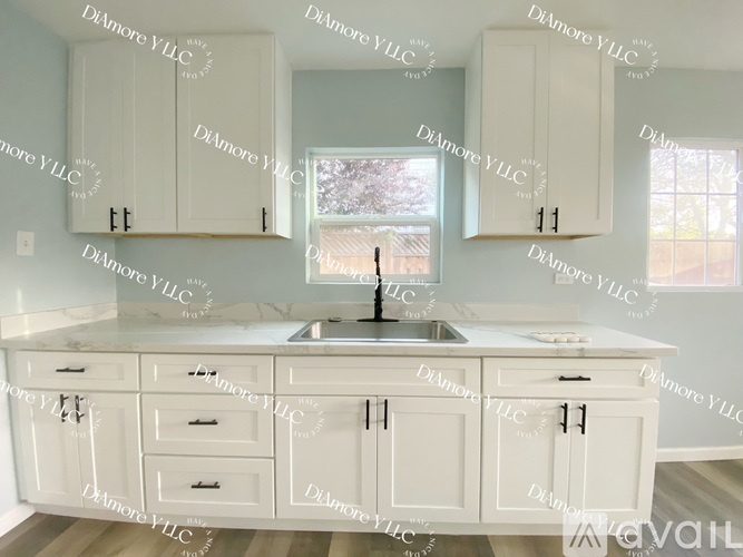 A kitchen with white cabinets and a marble countertop.