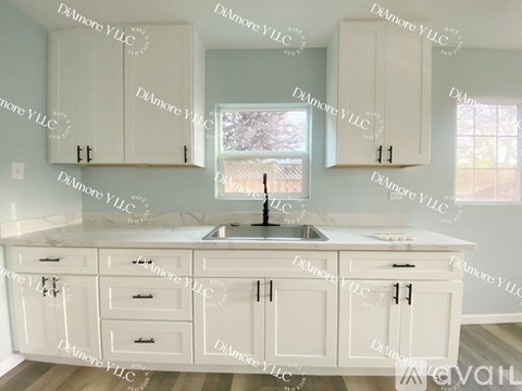 A kitchen with white cabinets and a marble countertop.