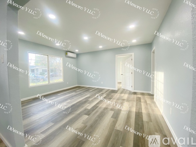 A room with wooden flooring and a door leading to another room.