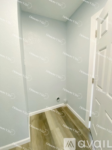 A hallway with a wooden floor and white walls.