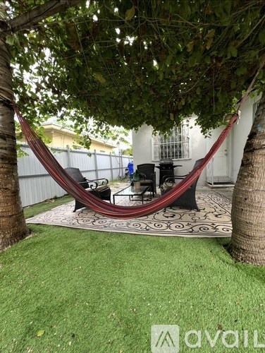 A hammock is strung between two trees in a backyard.