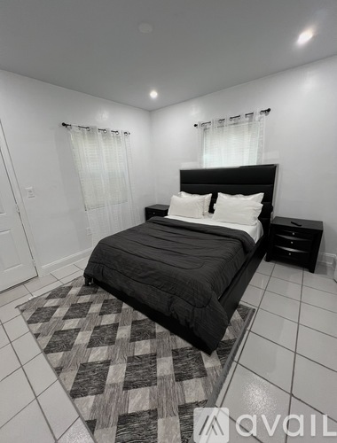 A bedroom with a black bed and a checkered rug.