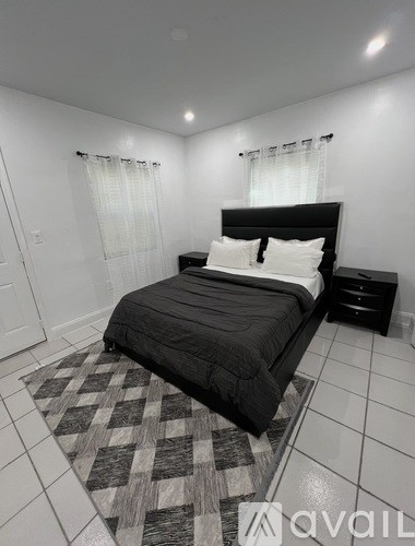 A bedroom with a black bed and a checkered rug.