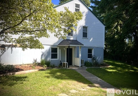 A white house with a black roof and a small porch.